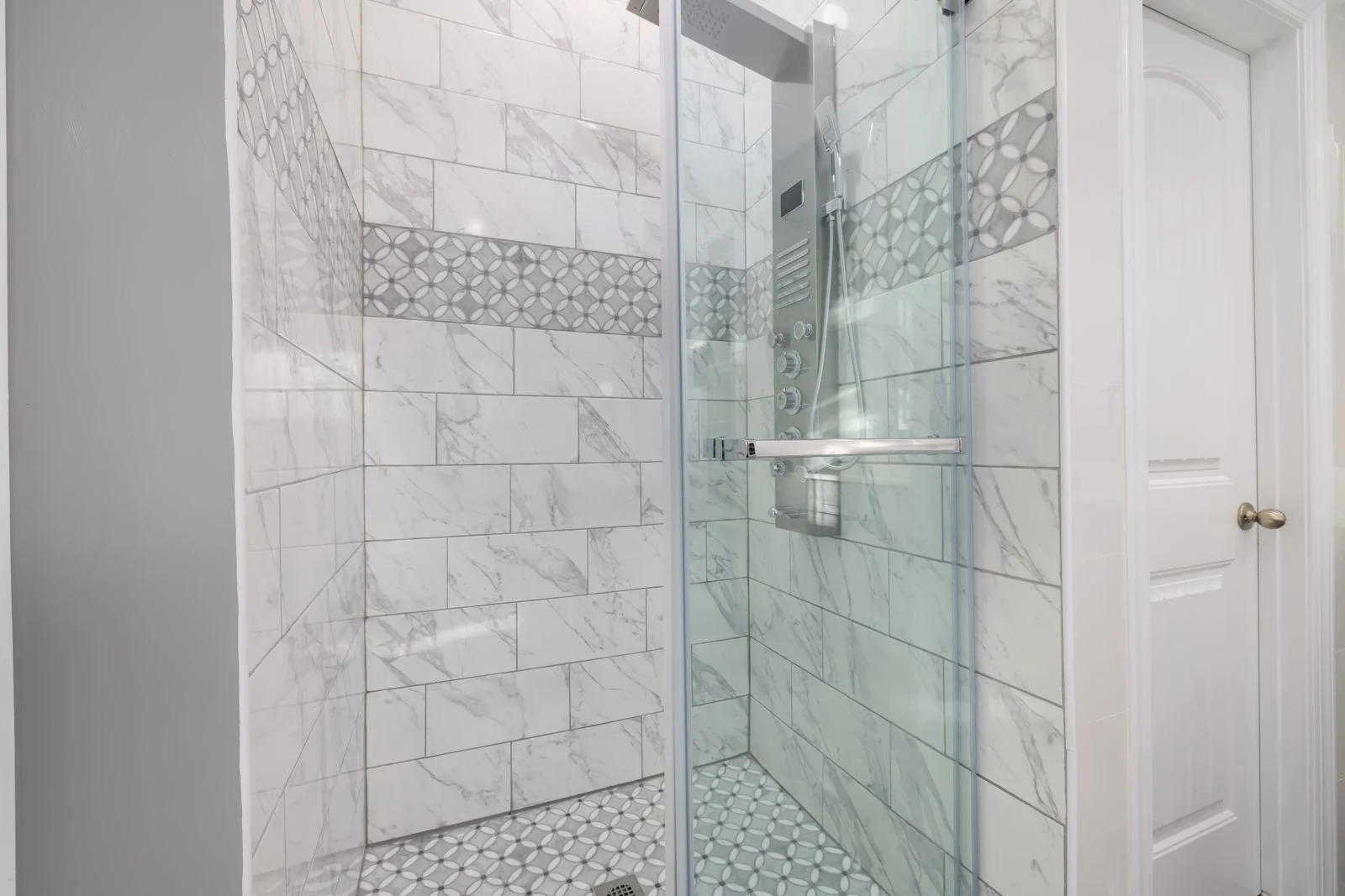 Sleek bathroom shower with marble tiles and glass door, showcasing modern interior design