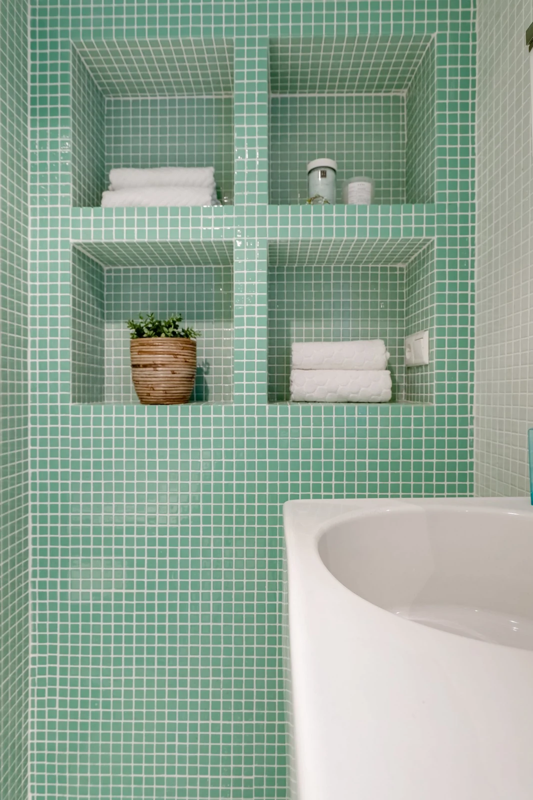 Recessed storage shelves above a bathroom basin