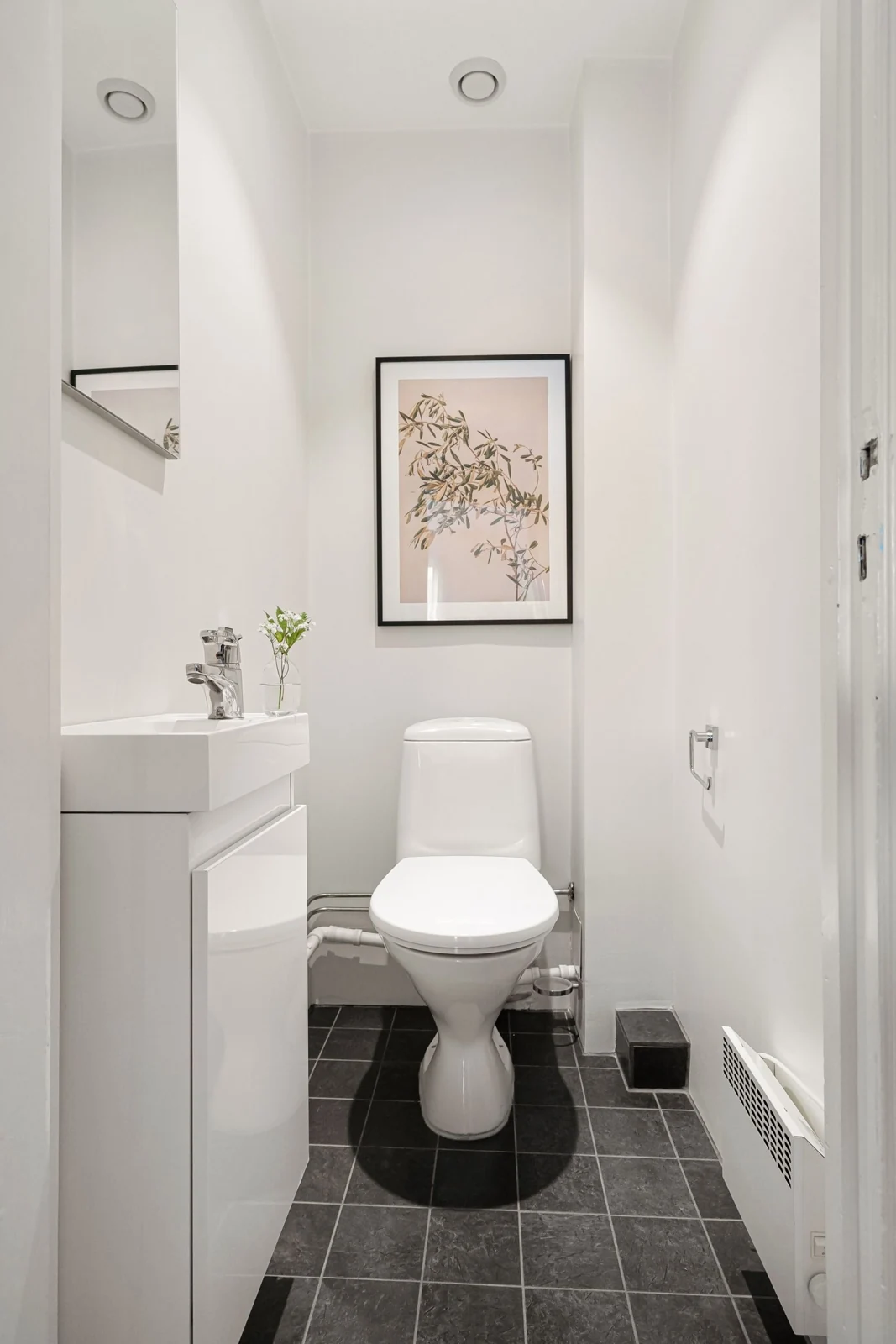 Elegant white bathroom featuring modern design and artistic decor in a compact layout