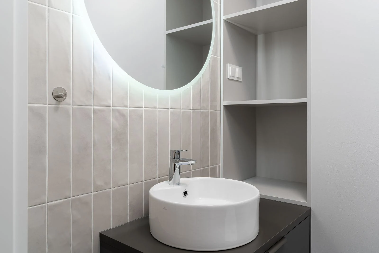 Sleek bathroom vanity with a round mirror and ceramic basin. Perfect for modern interiors