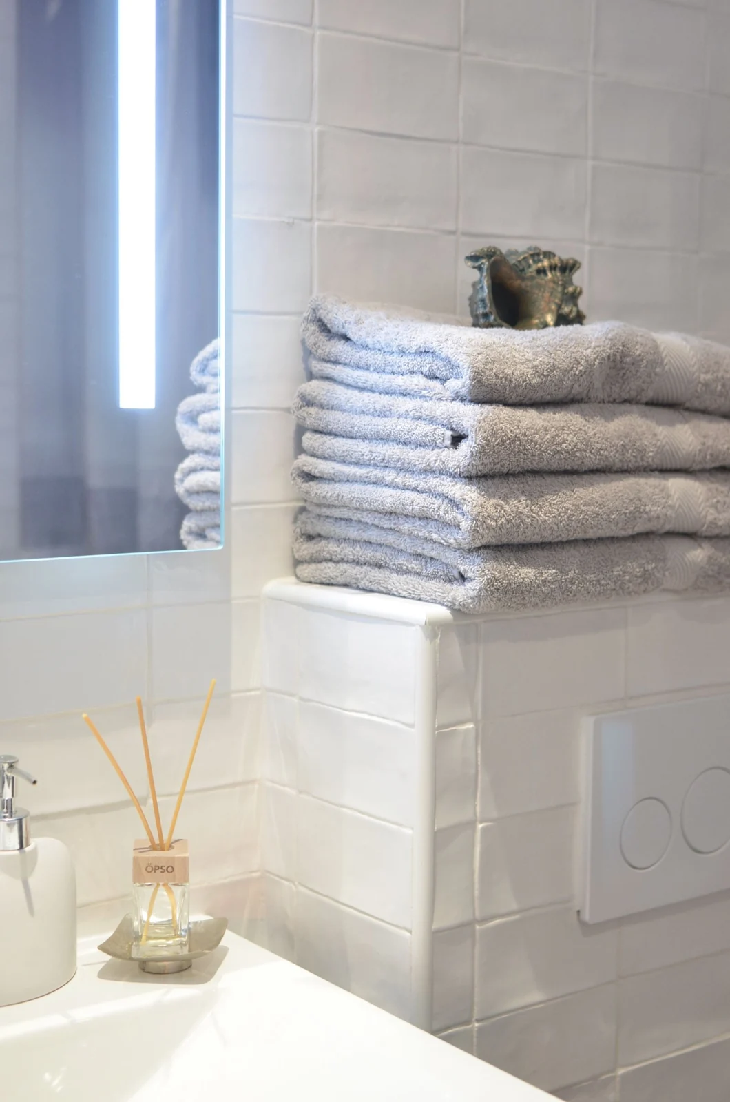 Folded towels beside a bathroom mirror