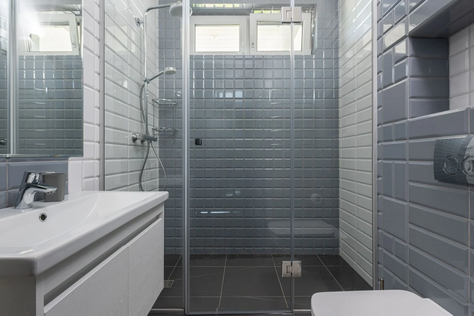 Modern design of gray and white tiled washroom with small windows under ceiling and geometric walls surface