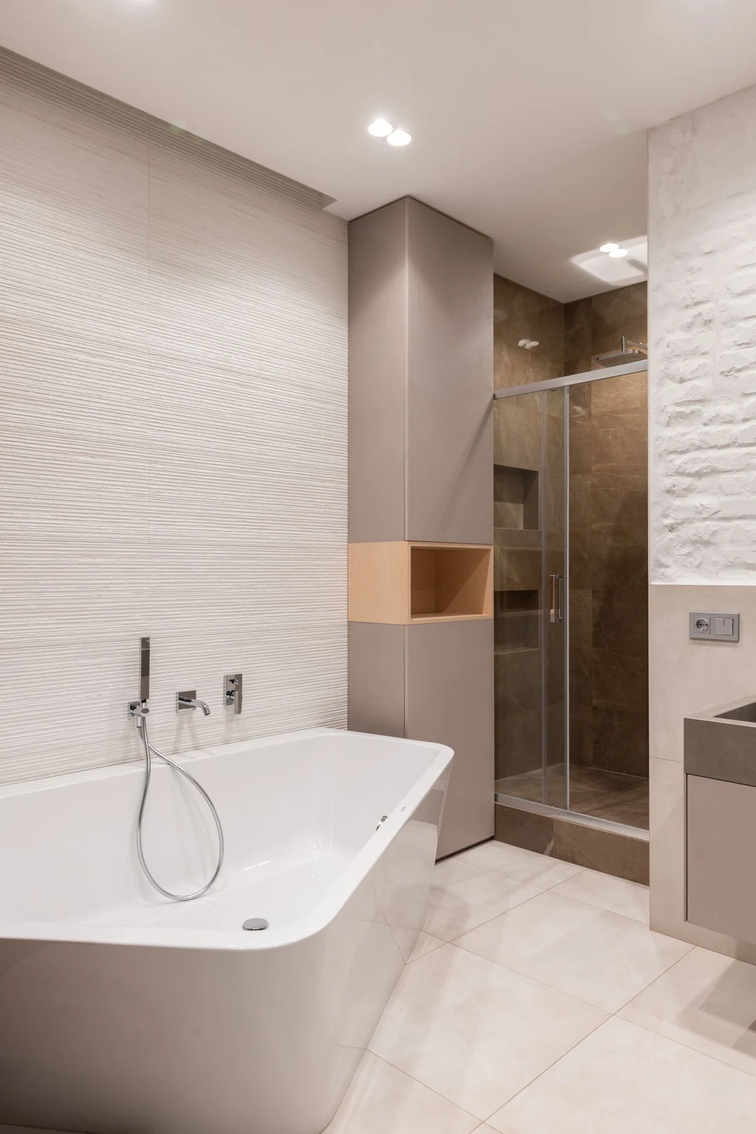 Interior of bright modern bathroom with bath with faucet next to shower and counter