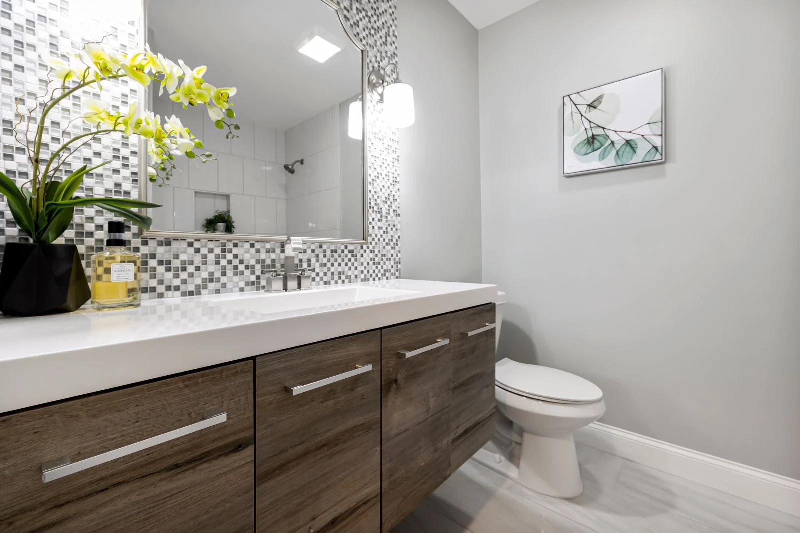 A stylish bathroom interior featuring a modern wooden vanity, decorative tiles, and indoor plants