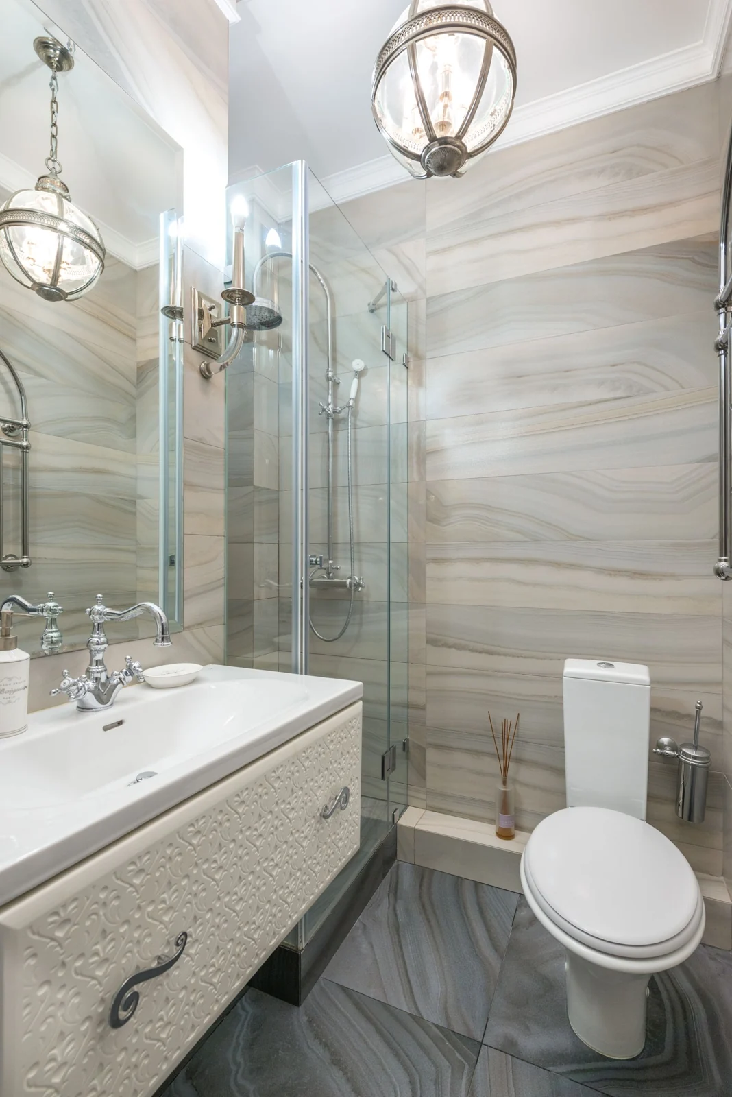 Interior of narrow modern bathroom with white basin and mirror next to shower cabin and toilet in modern apartment