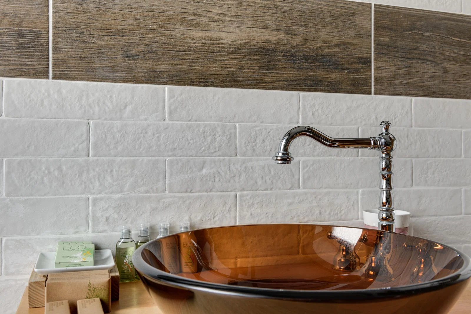 Elegant bathroom interior featuring a glass bowl sink with sleek chrome faucet and stylish tile backdrop